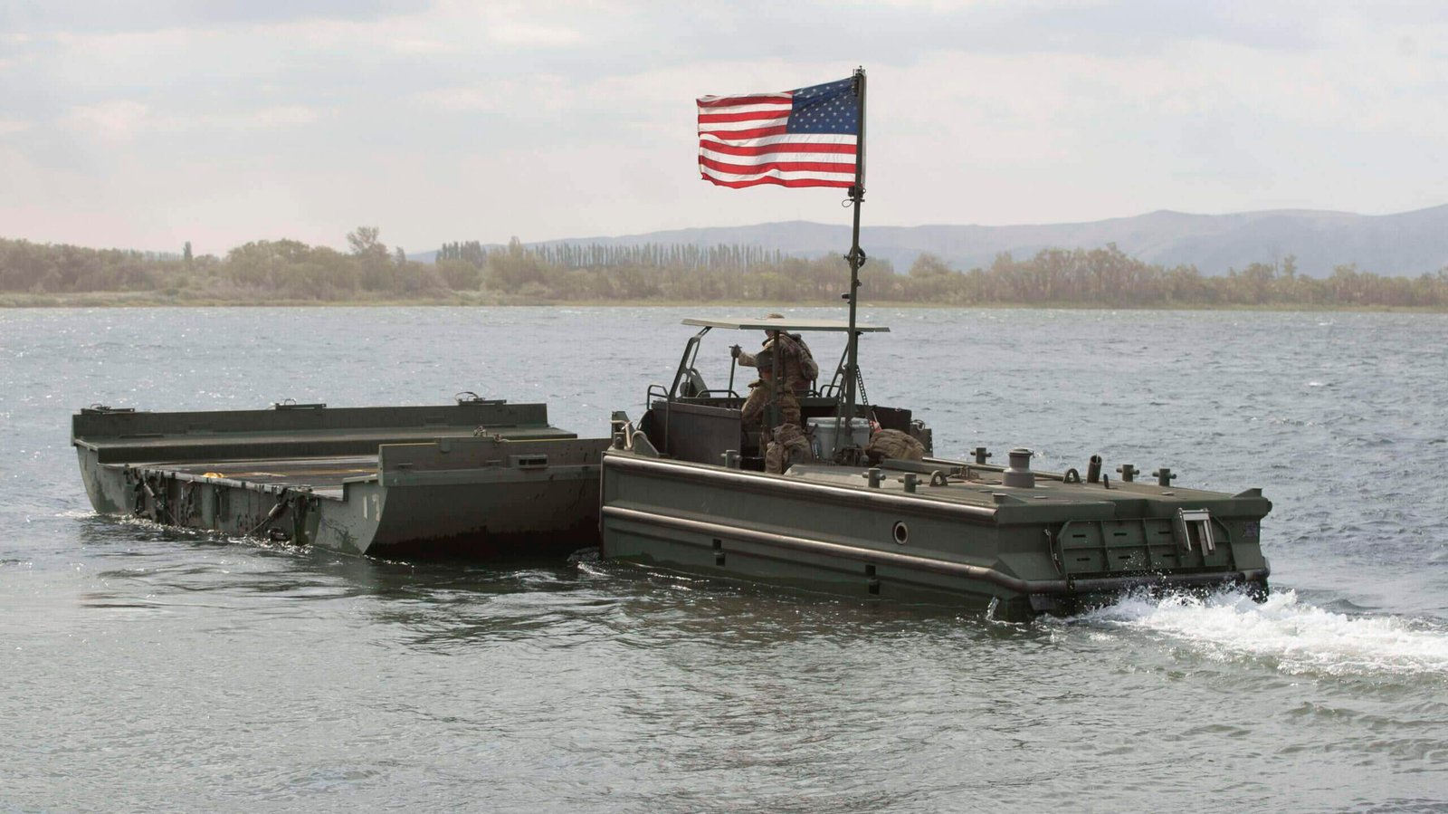 A Soldiers, with the 671st Multi-Role Bridge Company, operates a Bridge Erection Boat to move an Interior Bridge Bay to the far side of the Columbia River during Yakima Strike wet gap crossing. The bridge bay is used to form the Improved Ribbon Bridge used to transport weapon systems, trooops and supplies over water when permanent bridges are not available.